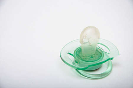 Nipple for children green. The child gnawed, tore the dummy. A hole in the dummy. Latex silicone on a white backgroundの写真素材