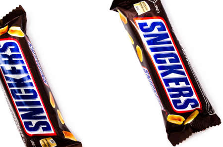 June 2020. Kiev, Ukraine. Two small single bars of snickers of 50 grams lie next to a white background. Top view and side view in macroのeditorial素材
