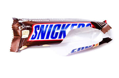 June 2020. Kiev, Ukraine. One torn package from under a small 50 gram snickers bar. Torn packing snickers on a white background in macroのeditorial素材