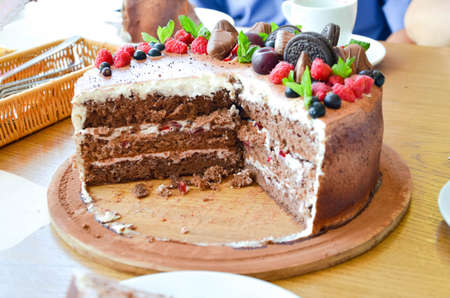 Chocolate cake in cocoa from above berries raspberries, black currant, biscuits, sweets on a round plate on the table. Cake slice, berries in macro. Birthday cake number 2. Top view, side view. Close-upの写真素材