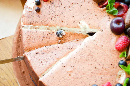 Chocolate cake in cocoa from above berries raspberries, black currant, biscuits, sweets on a round plate on the table. Cake slice, berries in macro. Birthday cake number 2. Top view, side view. Close-upの写真素材