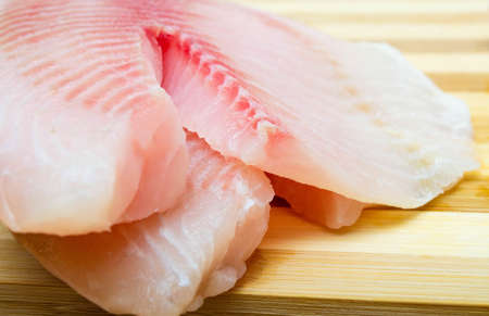 Two filet fish hare, rabbit fish on a cutting board in macro. Dorado fillet, telapia. Raw fish,...