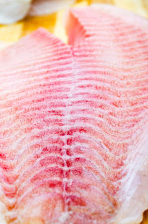 One filet of hare fish, rabbit fish on a cutting board in macro. Dorado fillet, telapia. Raw fish,...