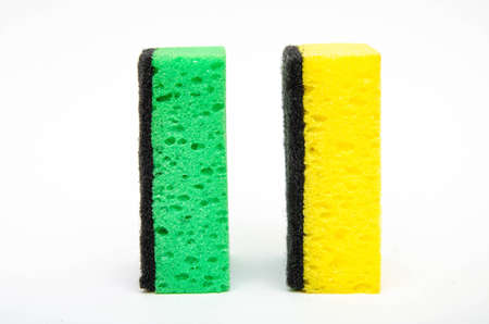 Sponge for washing dishes on a white background. Washcloth of green and yellow color. Two lips stand sideways and at an angle in the form of dominoes, lips stand verticallyの写真素材