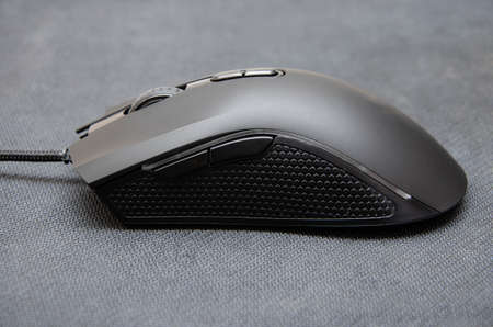 Black gaming mouse with side extra keys and a matte finish on a black background. A mouse from...