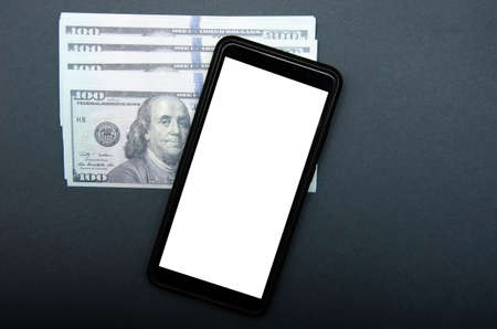 Dollars and smartphone. Denominations of 100 dollars are on a black background on them, next to them...