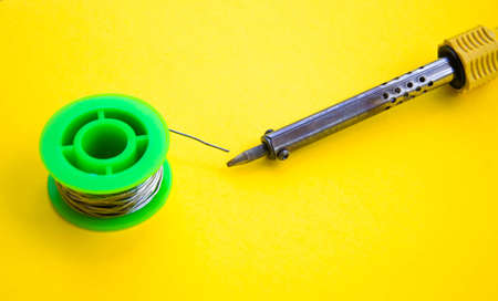 yellow Soldering iron, tin, rosin on a yellow background. Macro Repair of electrical equipment,...