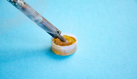 Soldering iron, tin, rosin on a yellow background. Macro Repair of electrical equipment, radio engineering. Solder wires, contacts. Copy spaceの写真素材