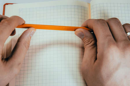 Men's hands, forearm hold a pen, notebook, smartphone. Hands write in notebook in a cell ideas,...