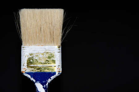 Used paint brush. Blue brush with a red tip in white paint. Macro photo. Repair brush in hand. Fibers copy spaceの写真素材