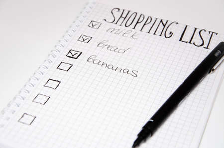Shopping list. Squared notebook with black pen on a white background. Record ideas, notes, plans,...