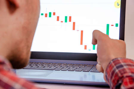 Trading on the exchange. Men's hands in a plaid shirt behind a laptop clenched into a fist....