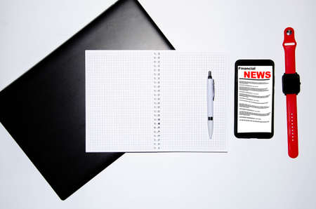 Smartphone on the screen the inscription financial news lies on a laptop smart watch and notebook...
