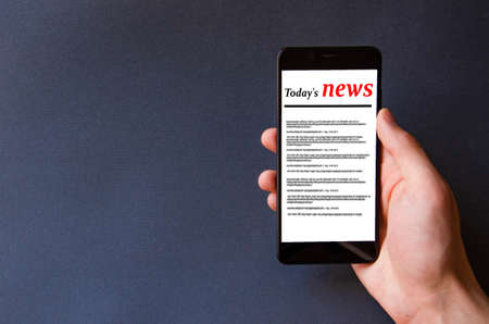Smartphone on the screen the inscription today's news in a male hand and on the table
