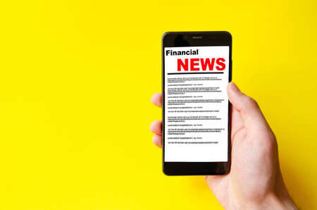 Male hand holds a smartphone on the screen the inscription financial news