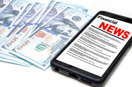 The smartphone on the screen the inscription financial news lies on dollars. 100 dollars banknotes...