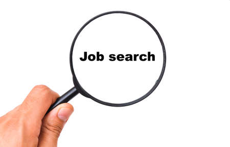 A man's hand holds a black magnifying glass by the handle on a white background in nookies written Job Searchの写真素材