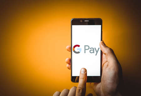 Google Pay. Smartphone in a male hand on the Google pay smartphone screen on a blue, yellow, black...
