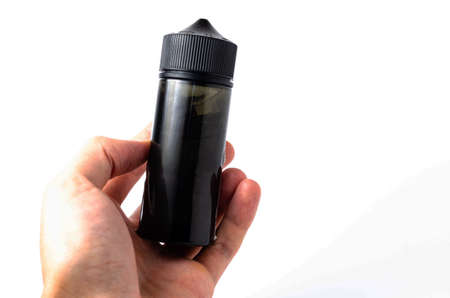 Black bottle, vial, bottle capacity 120 mm on white background in close-up, in a man's hand. Bottle with cap for childrenの写真素材