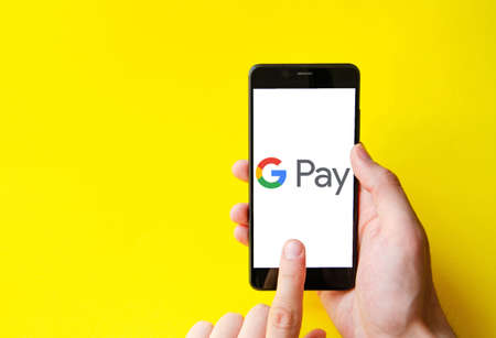 Google Pay. Smartphone in a male hand on the Google pay smartphone screen on a blue, yellow, black background. July 2020. Kiev, Ukraine.のeditorial素材
