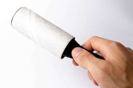 Roller for cleaning clothes on a white background in close-up. A flexible roller for cleaning clothes in a man's hand. Used, dirty clothes rollerの写真素材