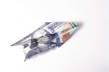 Burnt dollars. Burnt side view on a white background banknotes in close-up. Dollars in the form of a paper airplane on a white backgroundの写真素材