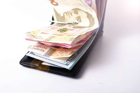 Banknotes Ukrainian hryvnia and dollars on a white background in close-up. Money in a black wallet, money clip Dollars and hryvniaの写真素材