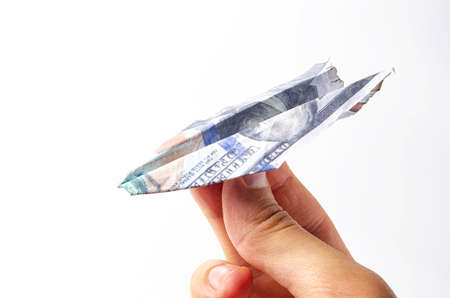 Burnt dollars. Burnt side view on a white background banknotes in close-up. Dollars in the form of a paper airplane on a white background in a man's handの写真素材