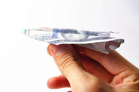 Burnt dollars. Burnt side view on a white background banknotes in close-up. Dollars in the form of a paper airplane on a white background in a man's handの写真素材