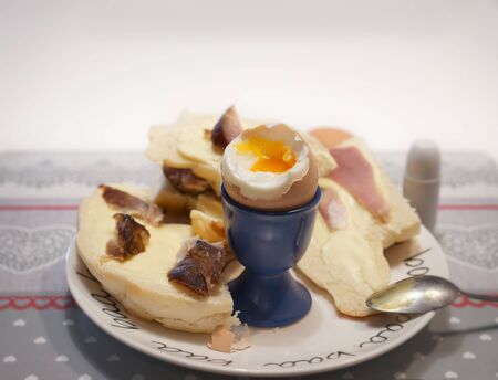 boiled egg in a cradle with visible yolk on a plate with a croissant
