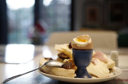 boiled egg in a cradle with visible yolk on a plate with a croissant