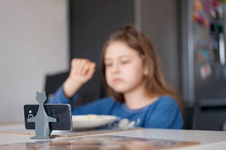 young teenager uses a smartphone during a meal at homeの写真素材