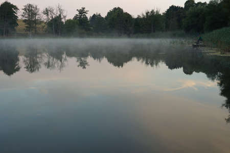 Przyton, Zachodniopomorskie, Poland - August 20, 2020: fog on a lake surrounded by treesのeditorial素材