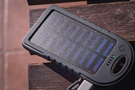 solar powered power bank on wooden table in the sunの写真素材