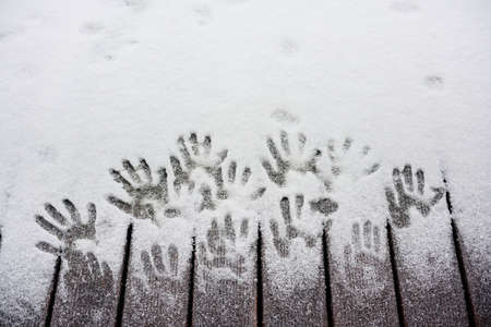 prints of human hands on snow-covered planksの写真素材