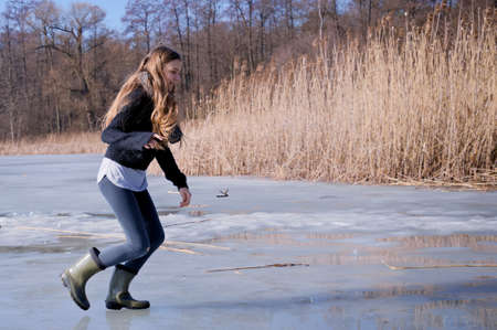 a teenager slides on the ice of a frozen lake