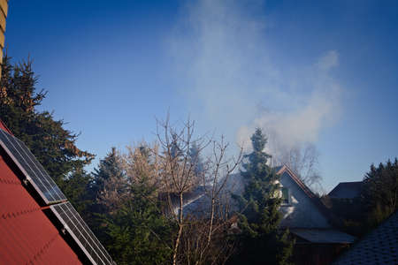 Smoke with chimney and roof with photovoltaic panelsの写真素材