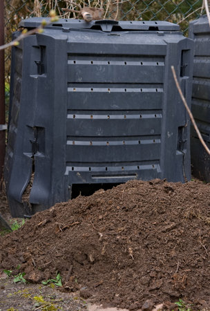 A stack of soil in front of the composter in the yard