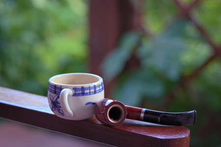 A mug of coffee and pipes on the terrace of a rural house in the morningの写真素材