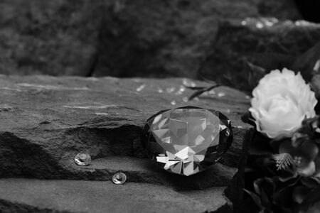 A Large Gem Stone on a Rock with Small Diamonds and Out of Focus Flowers