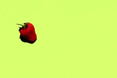 A Single Whole Strawberry on a Green Backgroundの写真素材