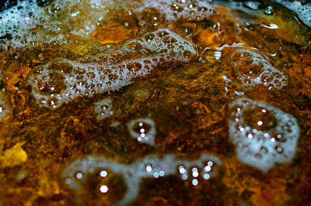 The water with the foam, which contains the chemical pollution. Shallow DOF.