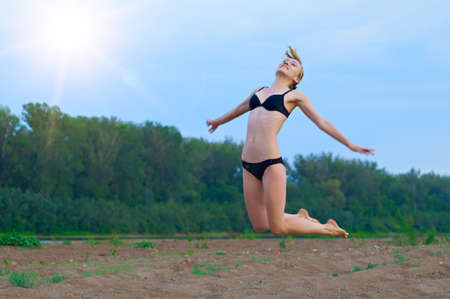 girl jumps high, resting on the sandy beachの写真素材