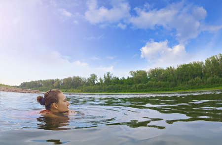 Young girl rests on nature, swimming in the riverの写真素材