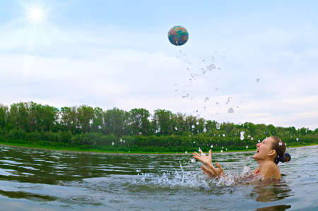 Joyful girl jumping and splashing in a river. の写真素材