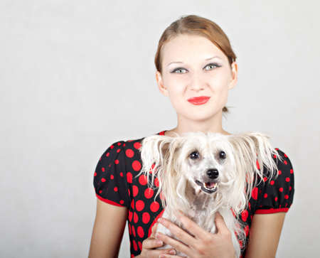 A beautiful girl with a dog in her arms. Chinese crested dog.の写真素材