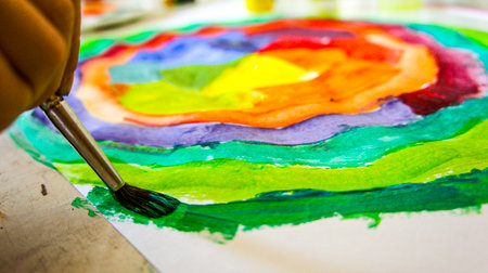 Closeup hand of child draws coloristic circle by paints gouache on white paper. Children create artist paints creativity vacation, training, drawing, color science, courses, painting, color science.の写真素材