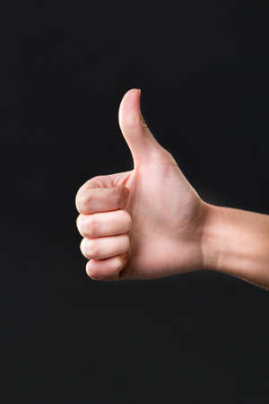 Thumb up female hand sign isolated with a dark backgroundの写真素材