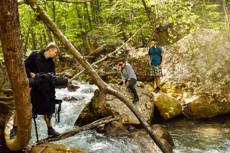 Hikers cross a river and help ech otherの写真素材