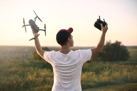 Silhouette of man holding drone quad copter and remote control enjoying freedom, victory, success....